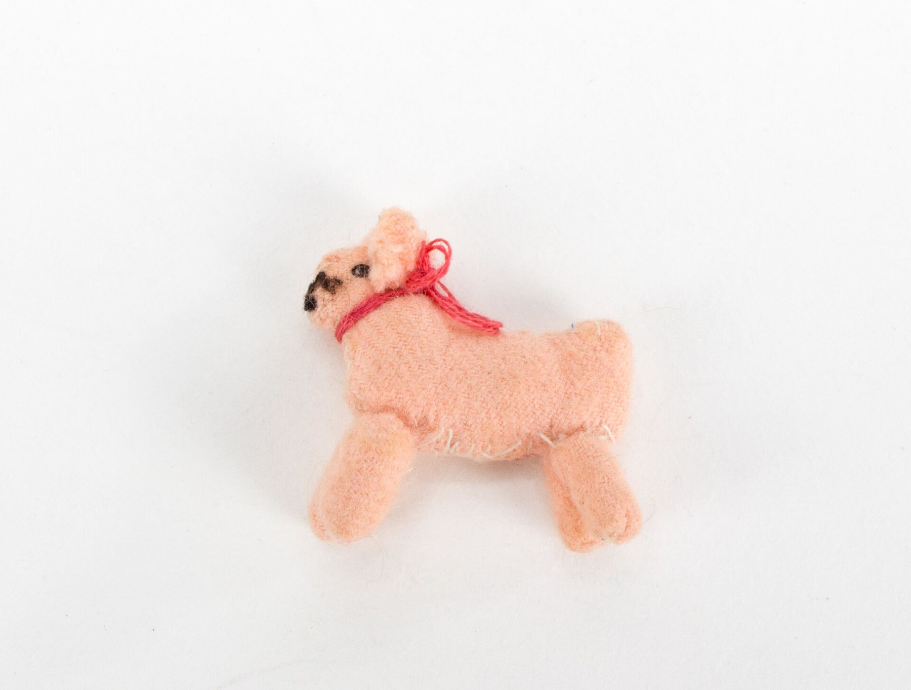 A small pink plush dog with a red collar