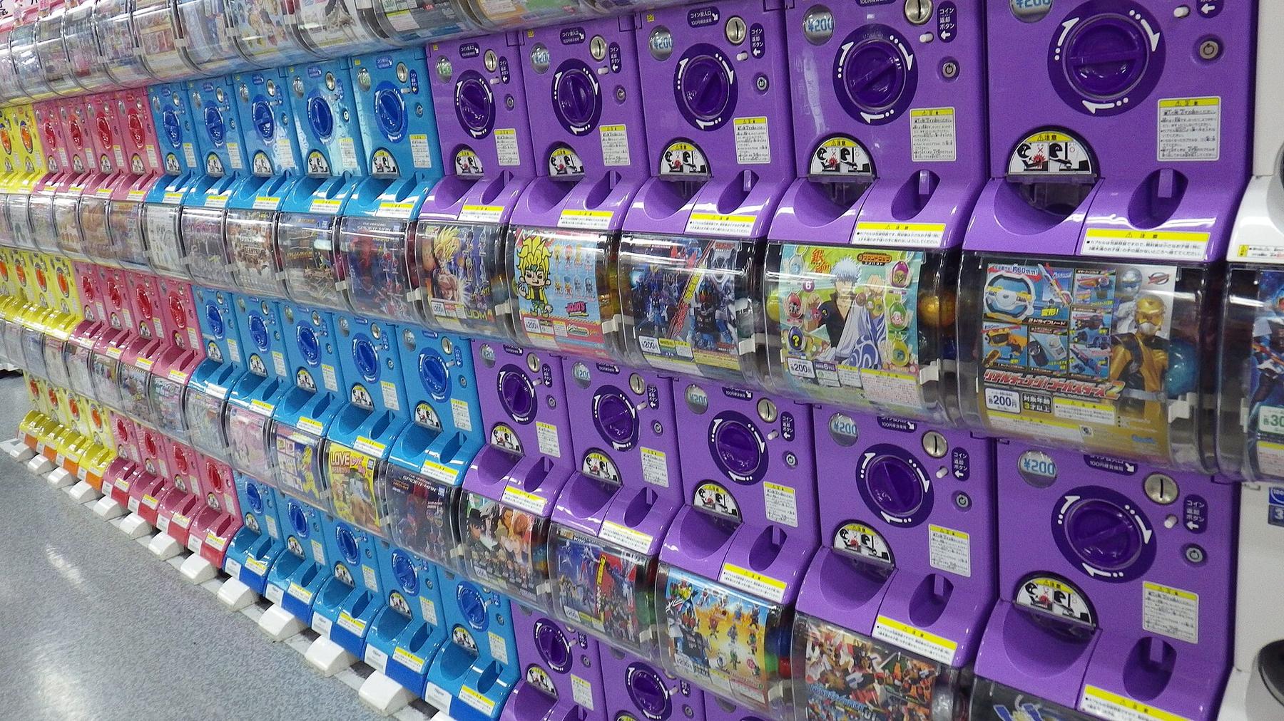 A long wall of purple and blue capsule toy machines