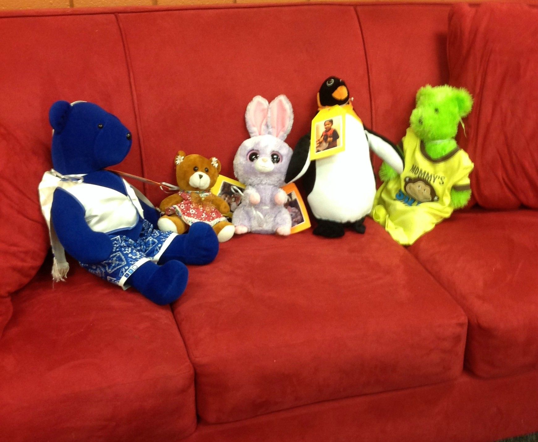 A row of plush friends sitting on a red sofa