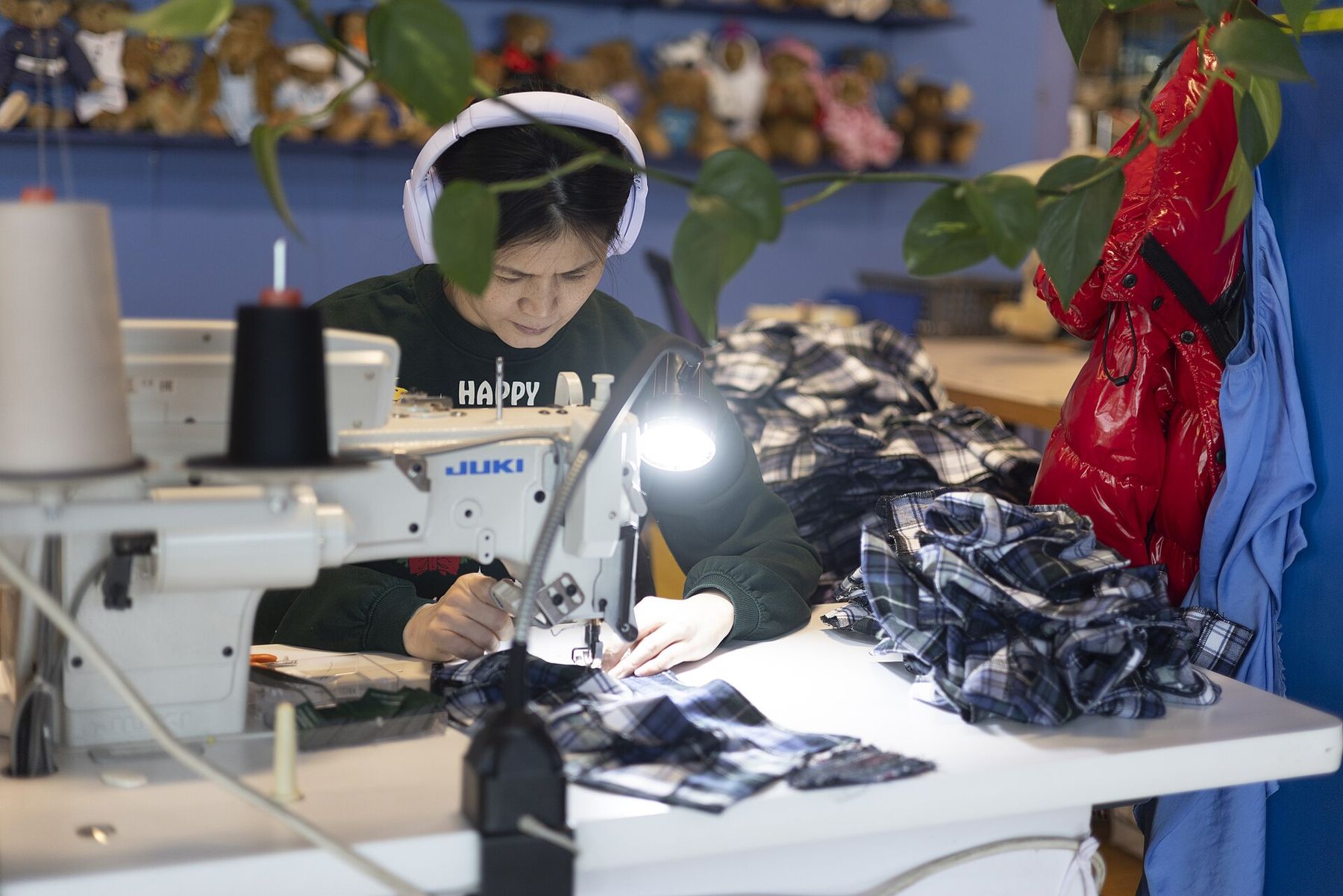 A maker stitching fabric at a sewing machine in a toy workshop