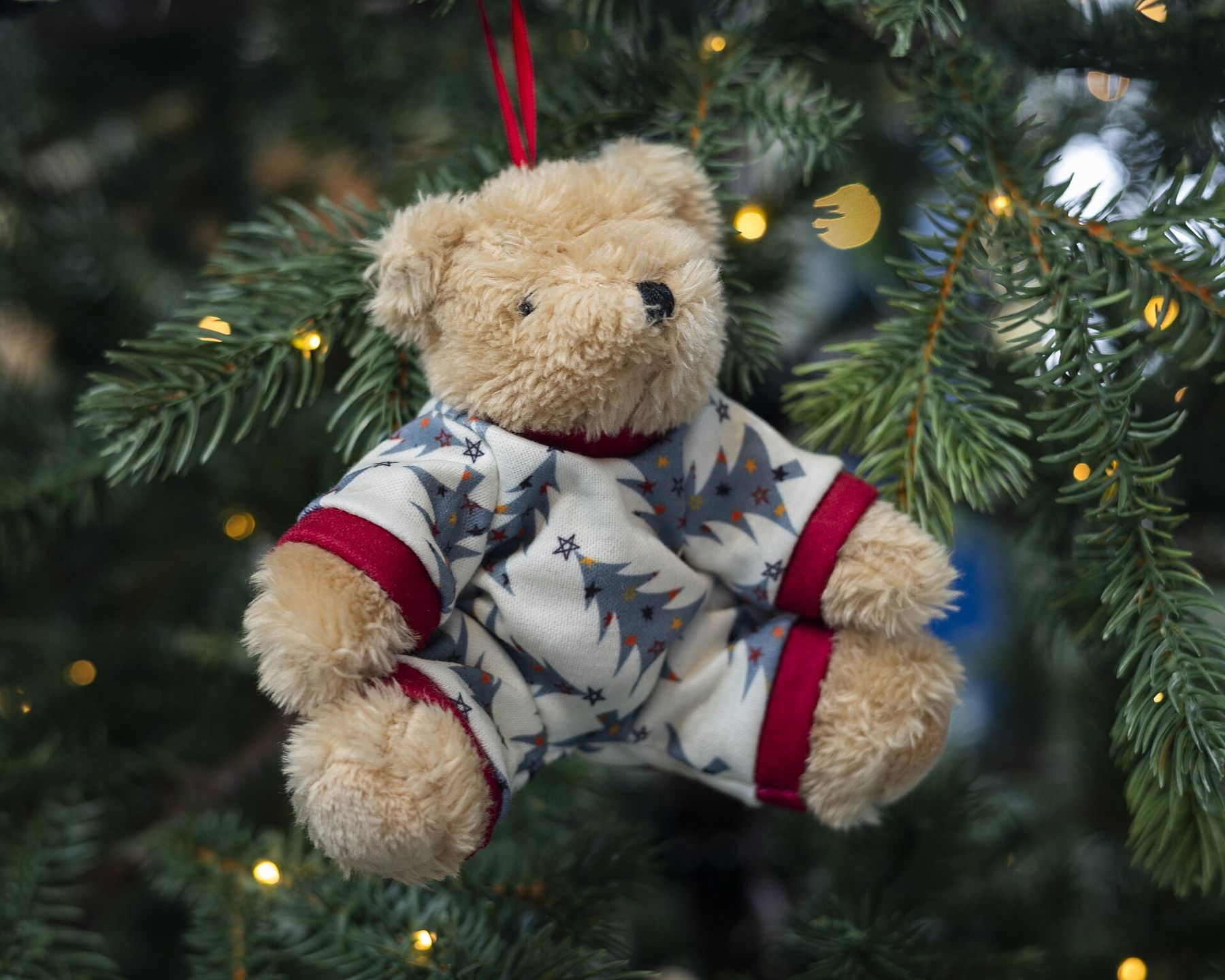 A teddy bear in pyjamas hanging on a Christmas tree